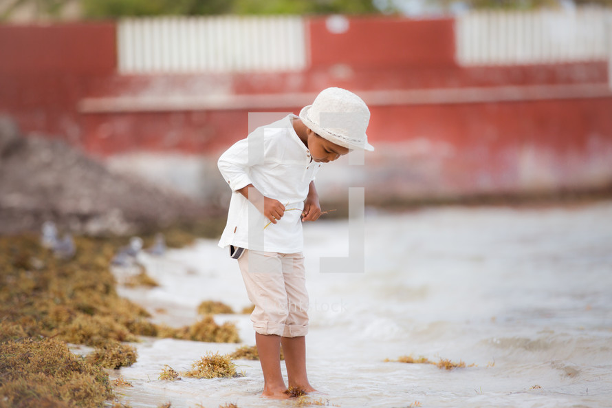 a boy dipping his toes in the sand 