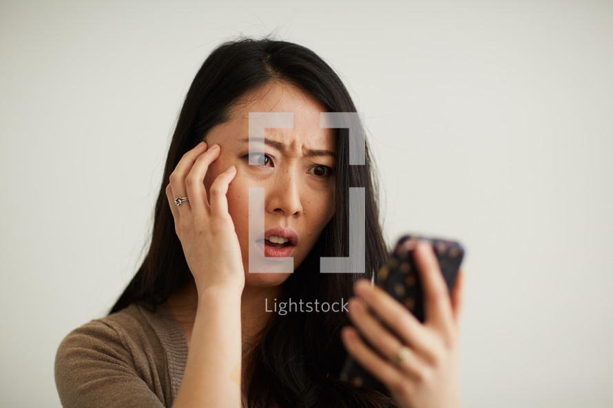 a woman reacting to something she saw on a cellphone screen 