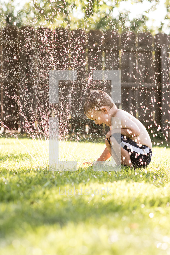 boy child playing in a sprinkler 