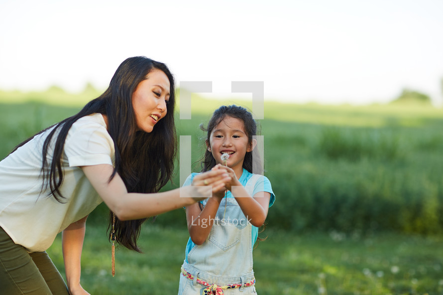 mother and daughter blowing dandelions 