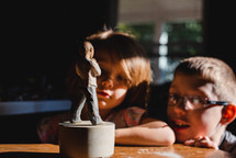 children looking at a figurine 