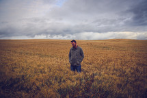 a man standing alone in a field of wheat 
