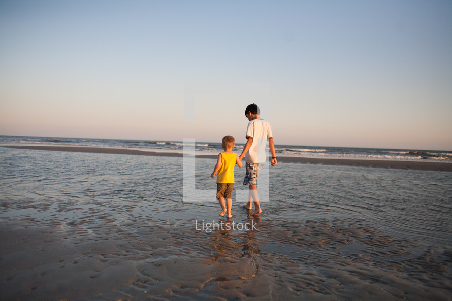 brothers walking holding hands on a beach 
