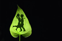 Silhouette Of Romantic Couple Embracing behind a Leaf