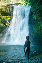 man looking up at a waterfall 