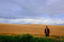a man standing alone in a field of wheat