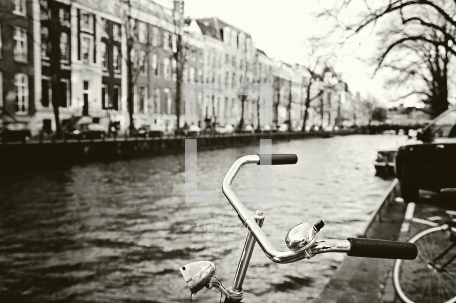 Bicycles parked on the edge of a canal in a city.