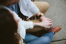 couple sitting on the pavement holding hands 
