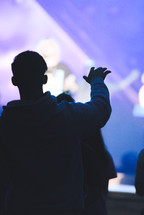 young man with hand raised during a worship service 