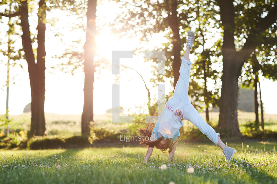 a girl doing a cartwheel in the grass