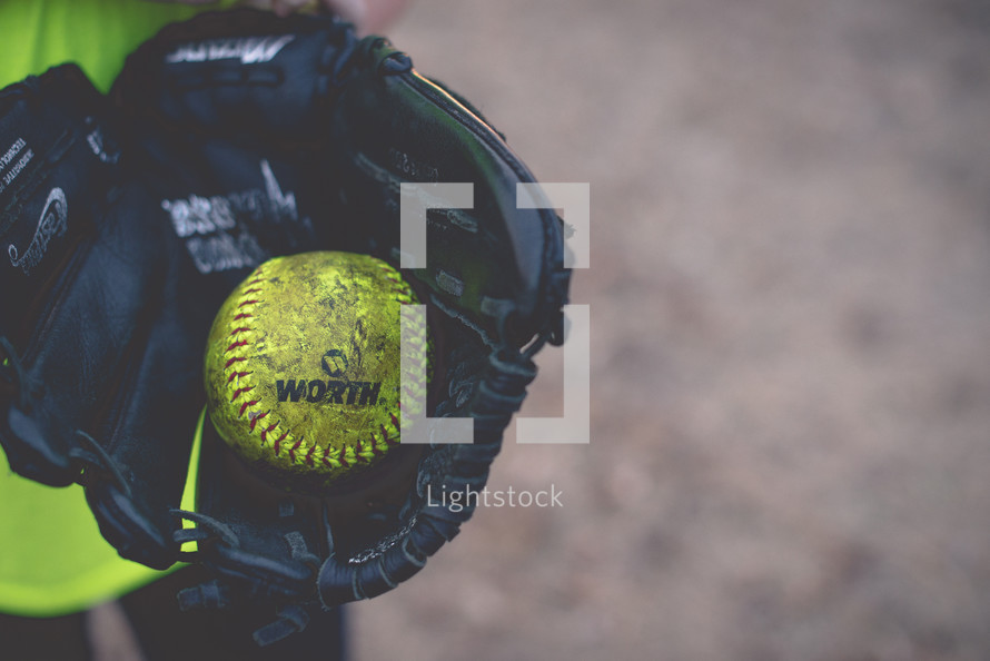 A baseball held inside a baseball glove.