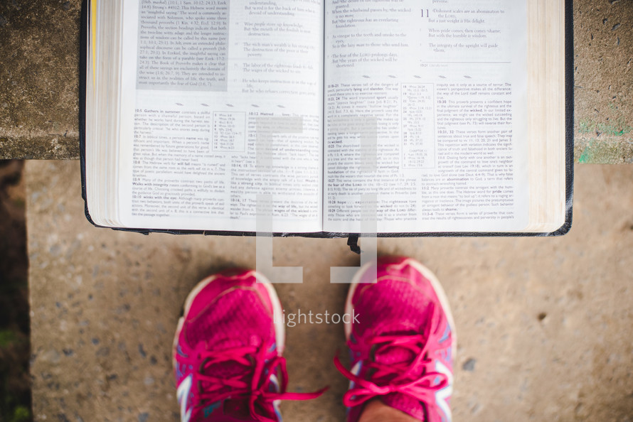 pink sneakers and open Bible on concrete 