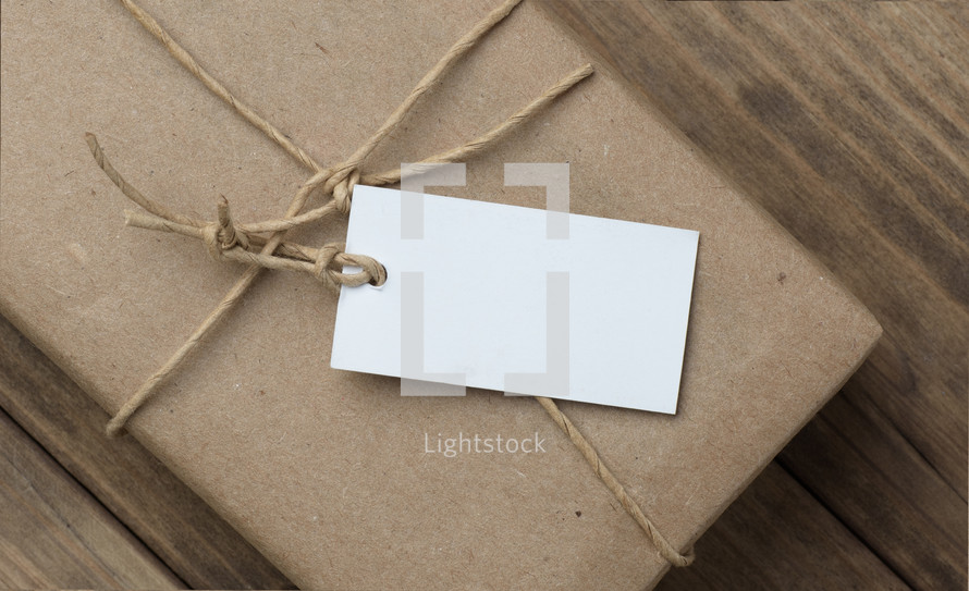 A white tag on a brown paper package tied with twine.