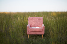 Bible in a chair in a field of tall grass 