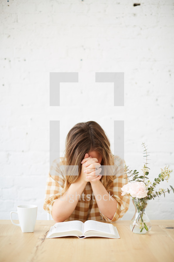 a woman praying over a Bible 