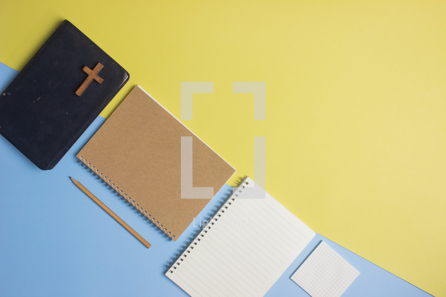Bible and notebook on a yellow and blue background 