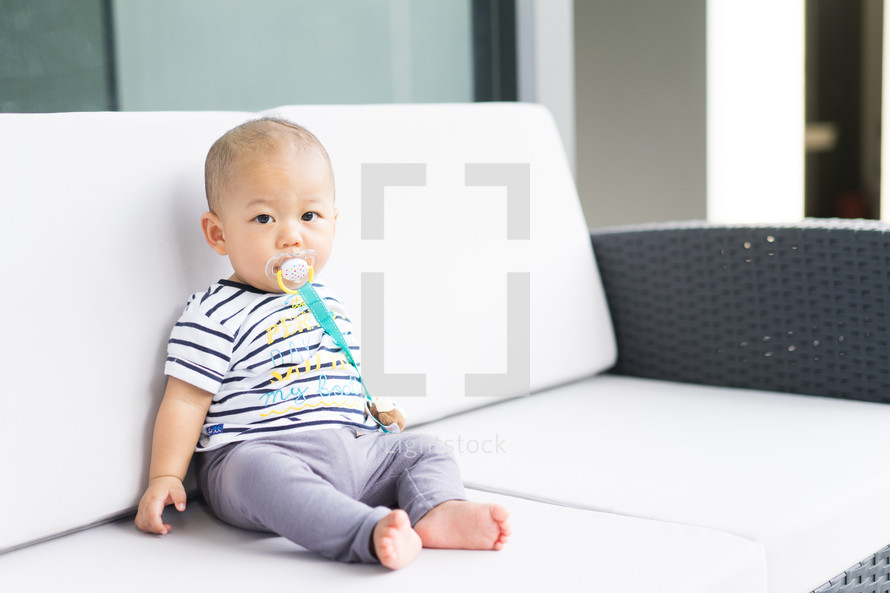 infant boy sitting on a couch 