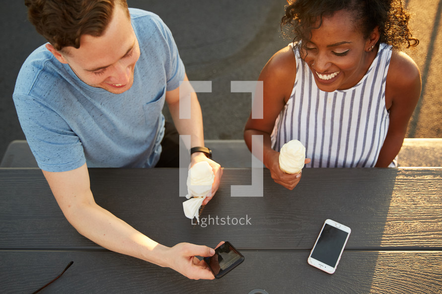 couple with cellphones and ice cream cones 