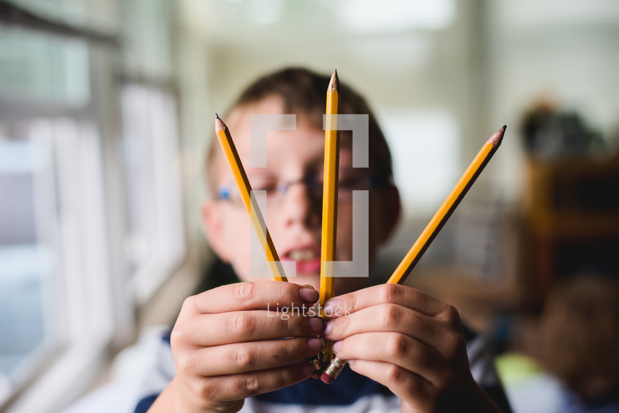 boy holding pencils 