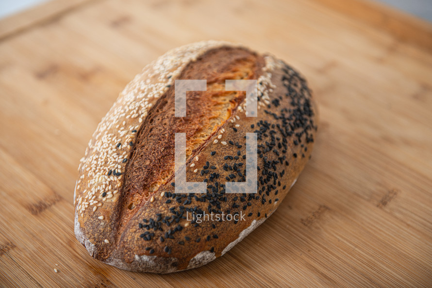 craft bread is sprinkled with white and black sesame seeds on a wooden background with copy space