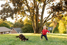  a toddler playing in the yard with a dog 