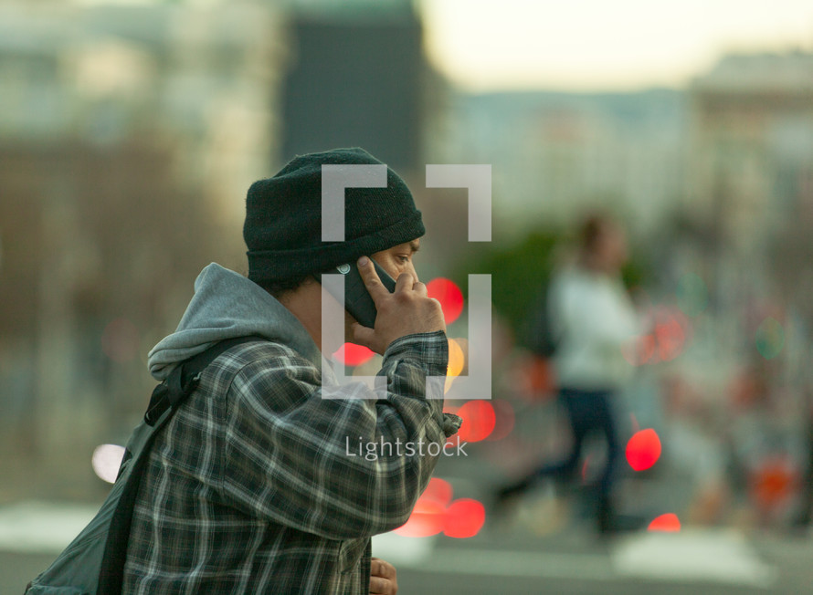 a man talking on a cellphone using a crosswalk 
