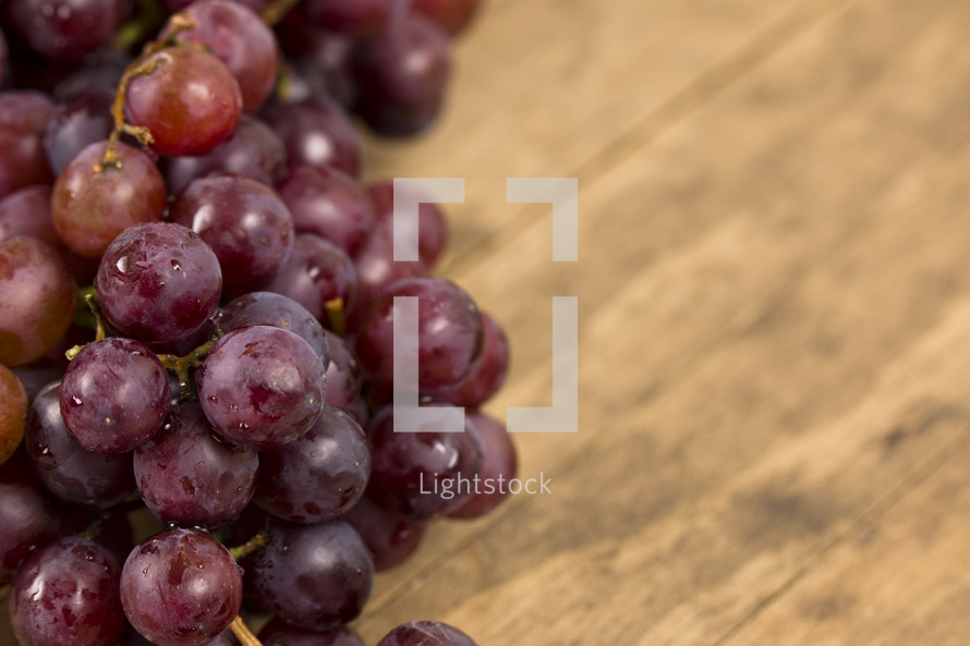 A cluster of grapes on a wooden table with room to write your own text