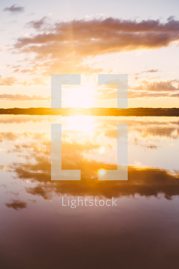 reflection of the clouds and sun on water 
