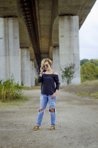 a young woman standing under an overpass 