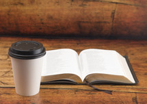 open Bible and disposable coffee cup 