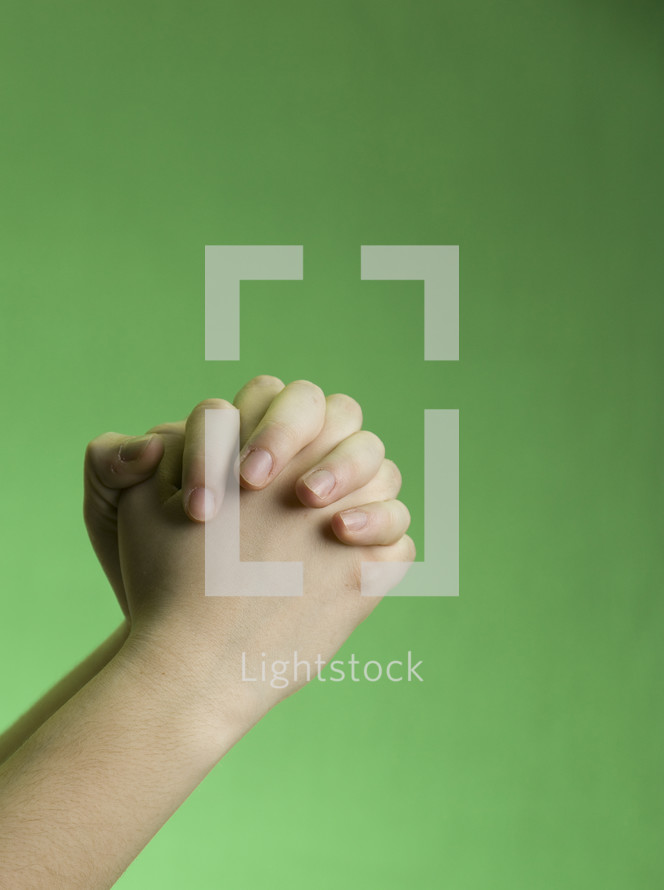 praying hands against a green background 