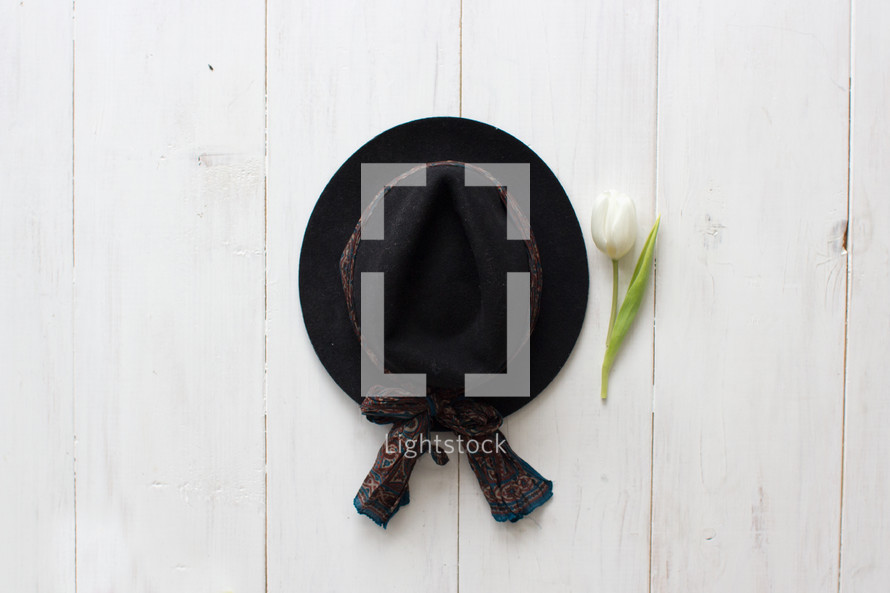 black hat and tulip on white wood boards 