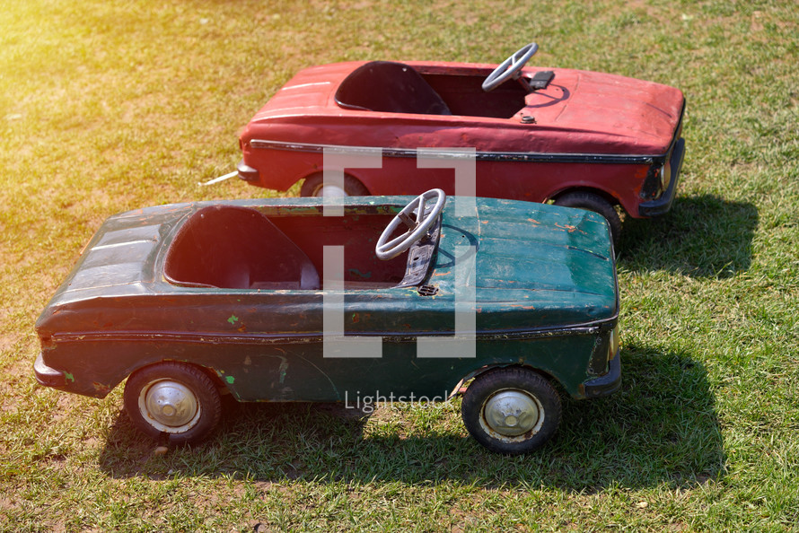 Green and red vintage toy cars on a green grass field. Side view. Sunset light