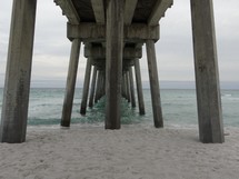 sand under a pier on a beach 