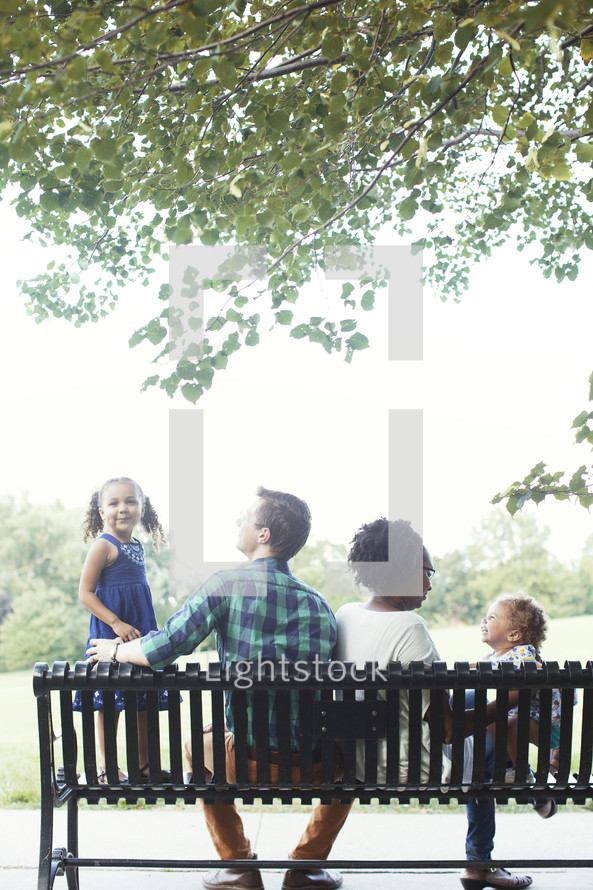 family sitting on a park bench 