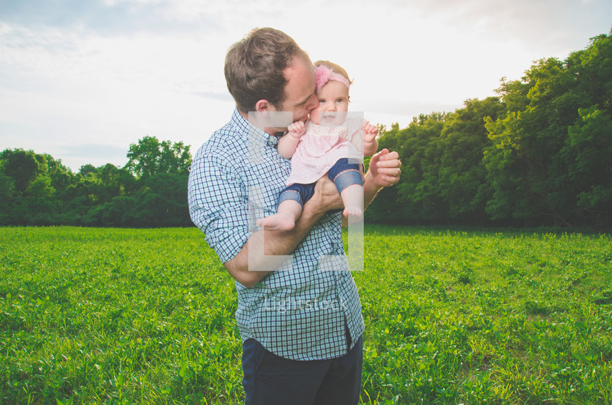 father holding his newborn daughter outdoors 