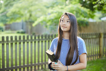 teen girl holding a Bible and looking up to God 