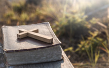 wooden cross on a Bible outdoors 