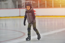 child ice skating wearing a helmet for safety 