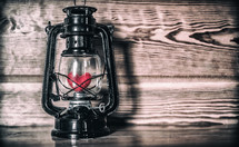 a red heart in a lantern against a wood background 