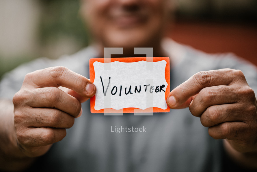 man holding a name badge with the word volunteer 