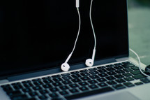 earbuds hanging over a laptop 