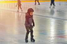 child ice skating wearing a helmet 