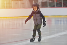 child ice skating wearing a helmet for safety 