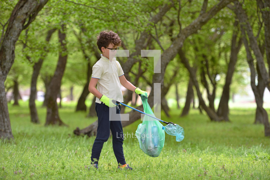 boy picking up trash outdoors 