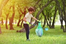 a young boy picking up trash outdoors 