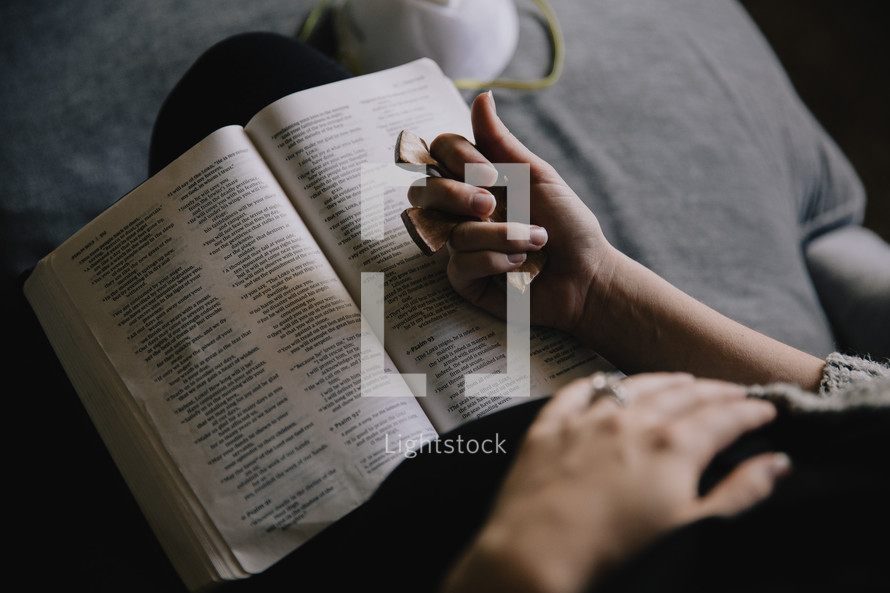 woman holding a cross and praying with a Bible 
