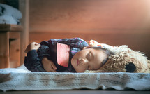 a sleeping child cuddling a Bible in bed 