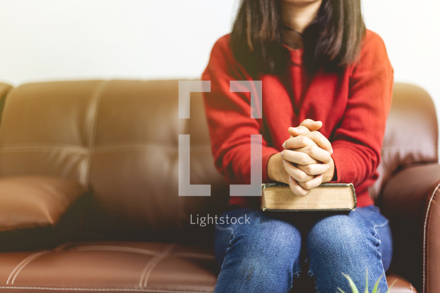a woman praying with a Bible in her lap 