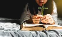 a woman holding a palm frond in the shape of a cross reading a Bible 